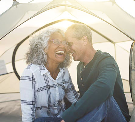 laughing mature couple in camping tent