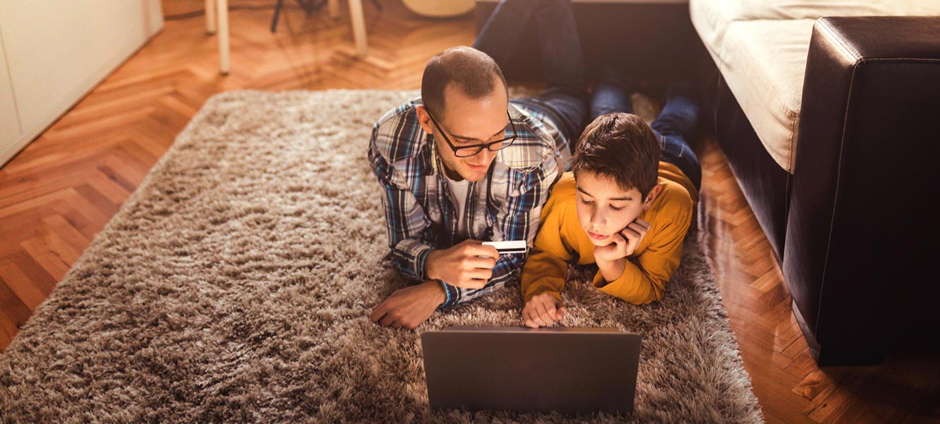 Father and son working on computer in living room