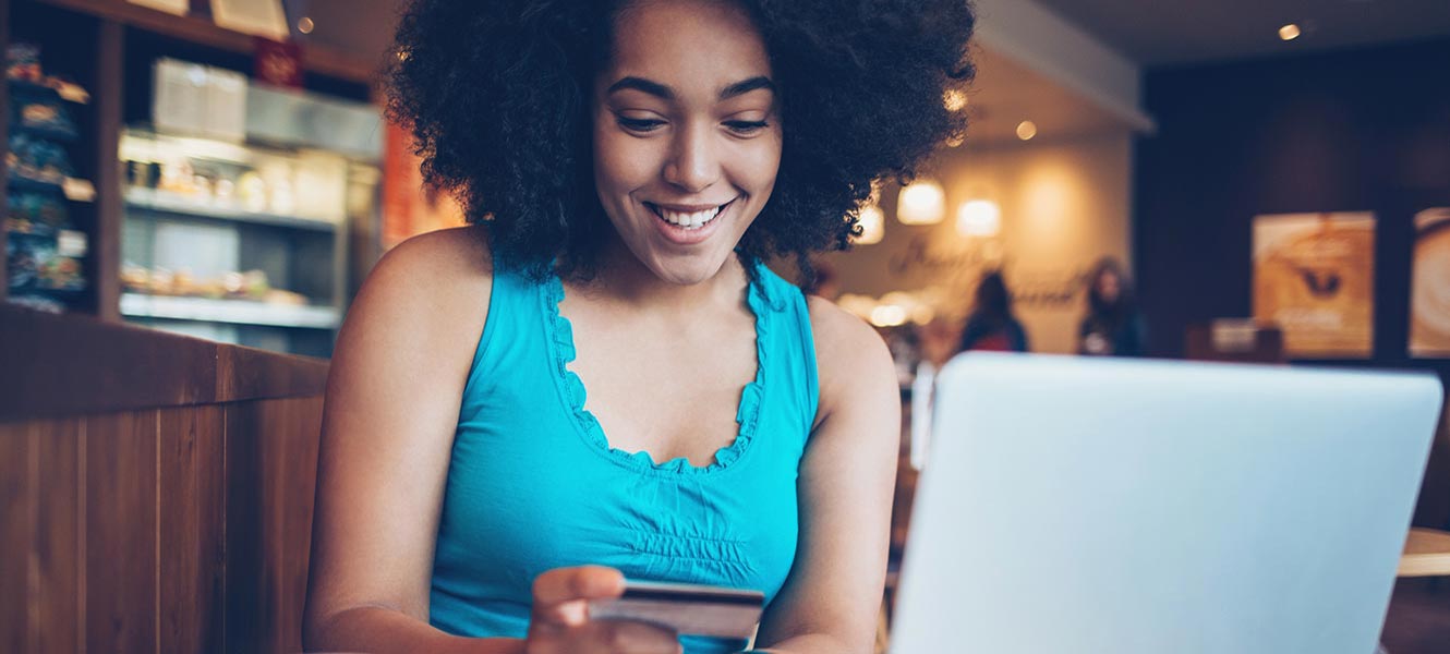 Woman in coffee shop using phone and computer