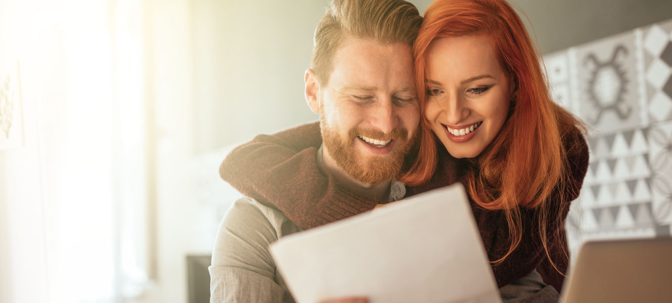 Couple looking at a document together smiling.