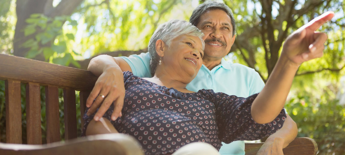 A Hispanic man and woman sitting on a bench.