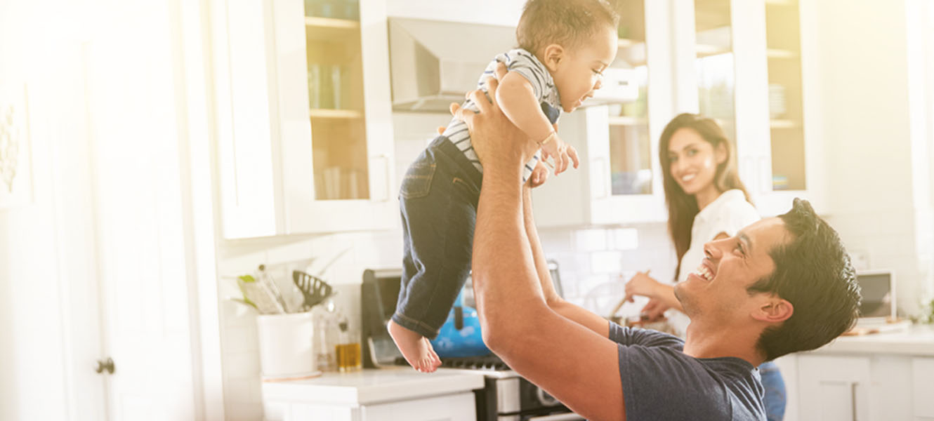 Mom and Dad in the kitchen holding a baby.