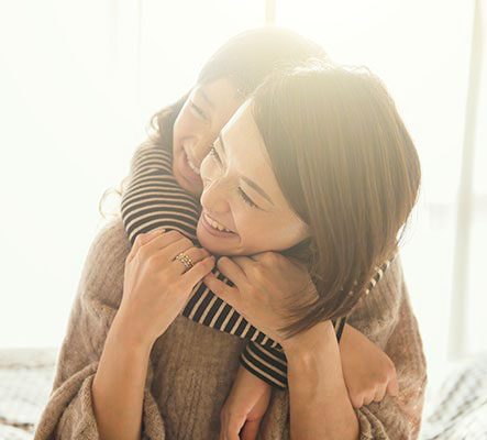 little girl hugging her mom from behind