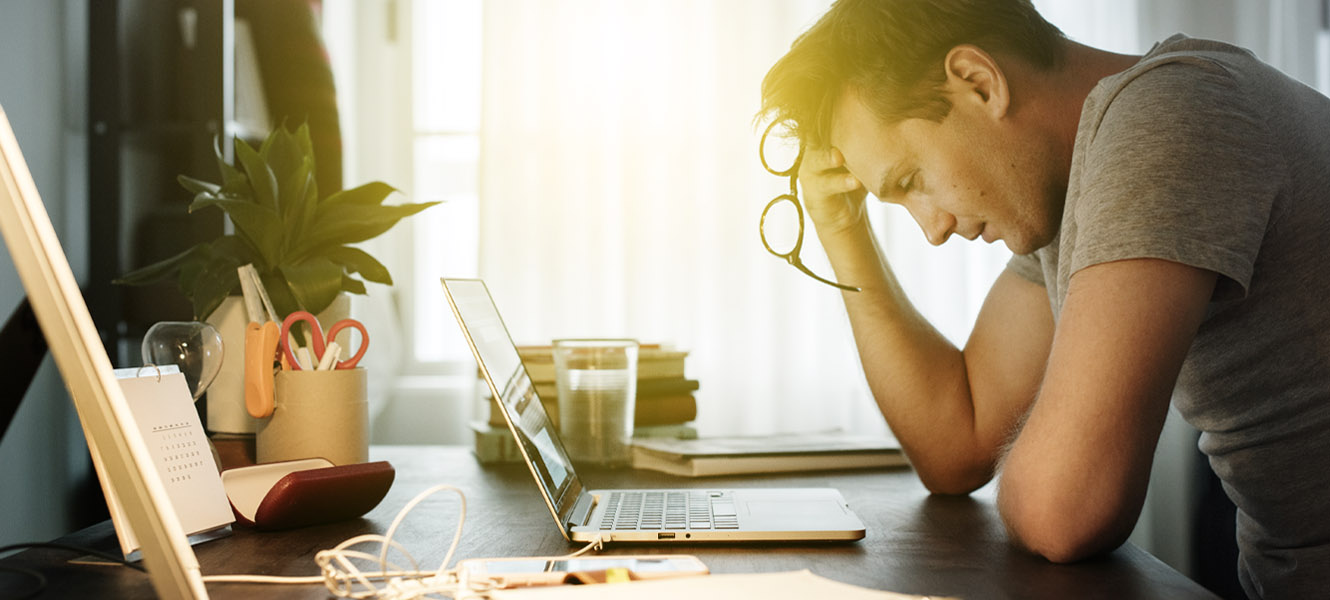 A frustrated man looking at his laptop.