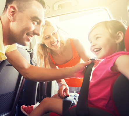 family strapping little girl in car seat