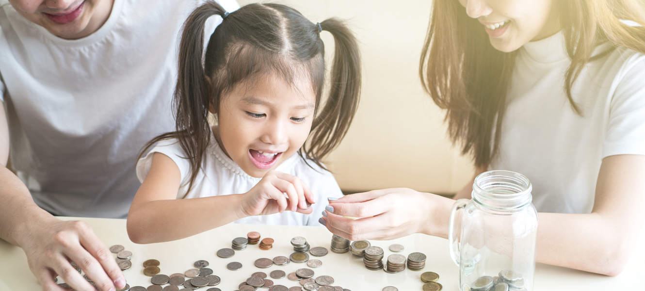 Mom and Dad counting money with their daughter at a table.