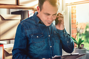 Man on phone looking down at clipboard